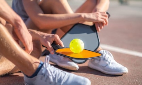 close up of some people holding pickleball paddles