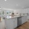 Kitchen with white cabinets and stainless appliances overlooking living area with large windows