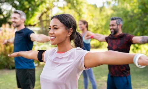 a woman exercising in a park with a group of people