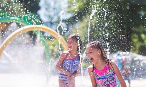a couple of kids playing in water at a splash pad